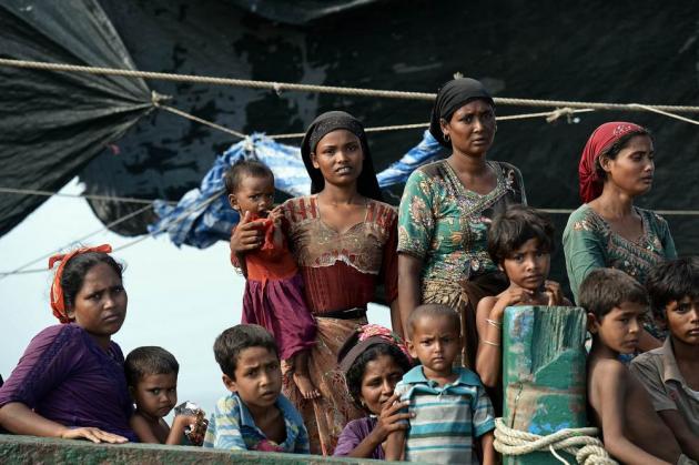 Rohingya migrants stand and sit in a boat cast adrift in the sea./AFP